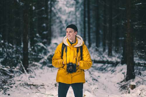 human person standing on snow in between trees people