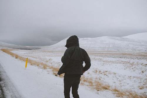 human person wearing black jacket walking on snow field at daytime people