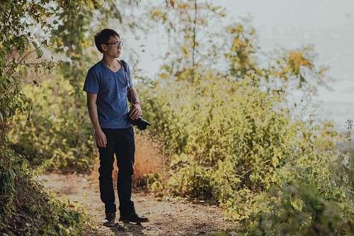 people person wearing shirt standing on forest with DSLR camera human