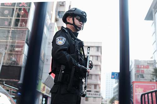 human police holding rifle while standing people