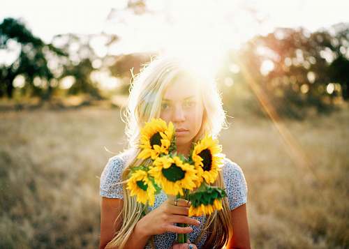 woman portrait photography of woman holding bouquet of sunflowers people