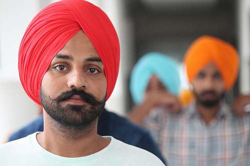 people selective focus photo of man wearing red pagri headdress turban