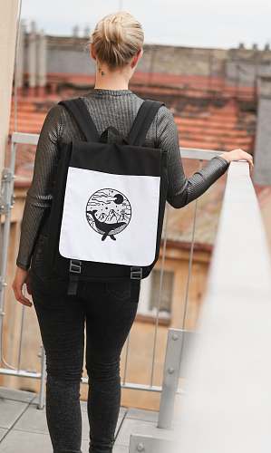 human selective focus photography of woman wearing black and white backpack standing on terrace while holding handrails people