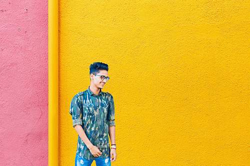 human smiling man standing near yellow and pink wall people