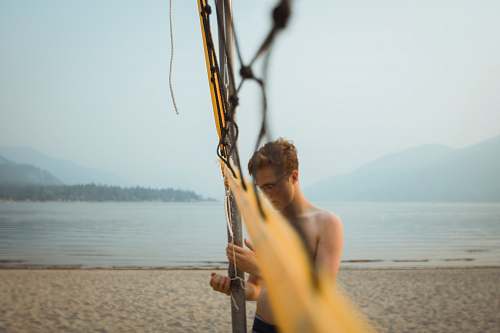 human standing man beside net on beach during daytime people