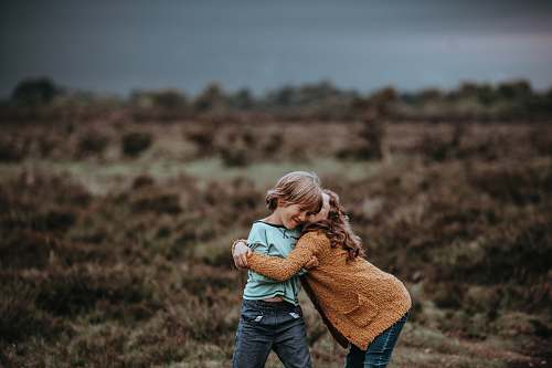 human two child hugging in front of field people