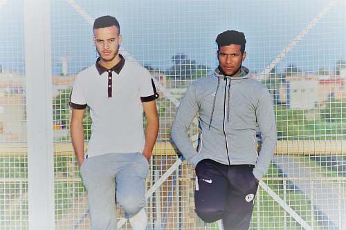 people two men standing in front of fence human