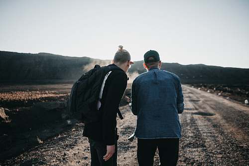 human two men standing on brown pathway people
