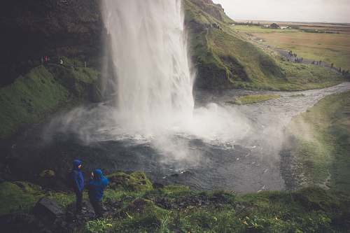 people two person wearing blue hoodie standing on ground in front of waterfalls human