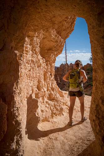 human woman carrying backpack standing in cave passage people