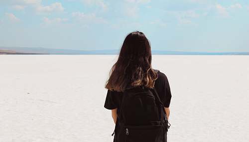 human woman facing white field with backpack at daytime people