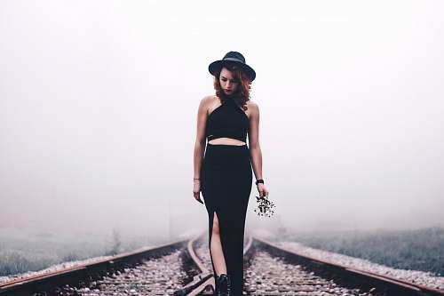 human woman holding flowers looking on train rails people