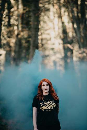 human woman in black t-shirt with teal smoke in selective focus photography people