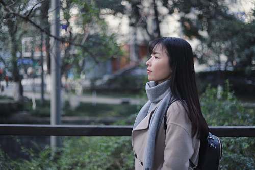human woman in gray scarf and coat standing near bridge people