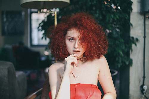 human woman in orange tube top touching her chin people