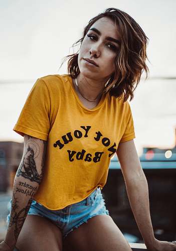 people woman in yellow crew-neck shirt and blue short shorts sitting on bench human