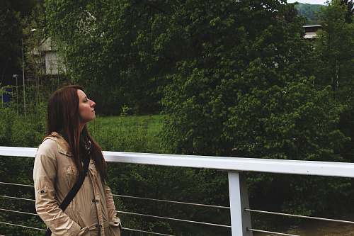 human woman looking up while standing near rail and trees people