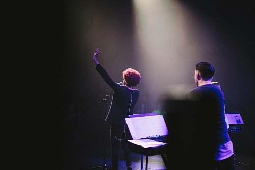 singer woman raising her hand beside microphone music