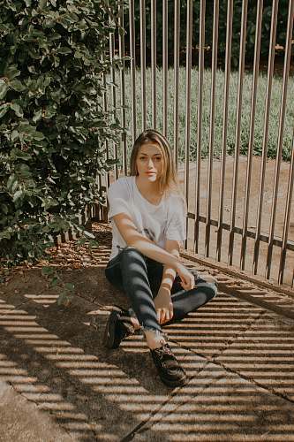 people woman sitting beside green bush and gray metal gate human
