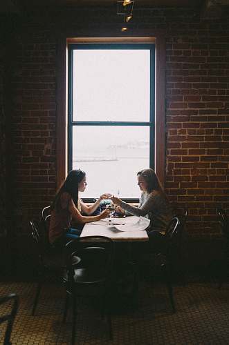 people woman sitting in front of woman near window human