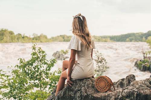 people woman sitting on rock beside body of water human