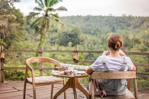 people woman sitting on wooden armchair facing forest human