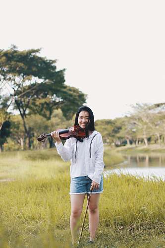 human woman standing holding violin near river people