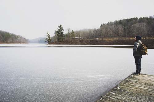 human woman standing in front of lake while staring at it people