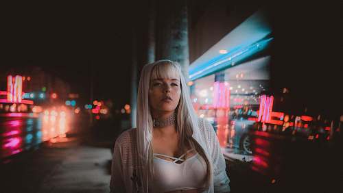 people woman standing near building beside road at nighttime human