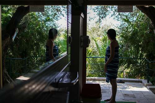 human woman standing near door facing trees during daytime people