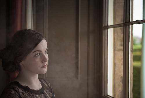 people woman standing near window looking outside human