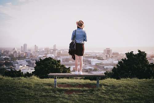 people woman standing on bench facing city skyline during daytime human