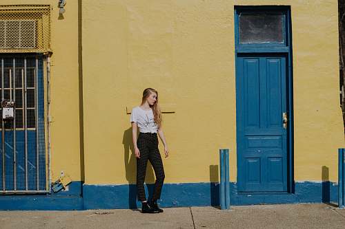 people woman standing on front of yellow painted wall between two doors human