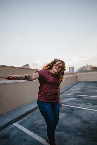 human woman standing on gray concrete floor while raising her left arm people