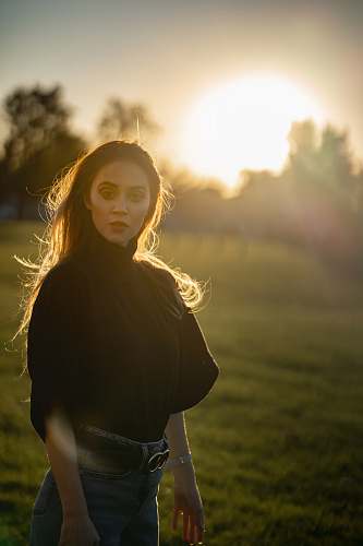 human woman standing on green grass during golden hour people