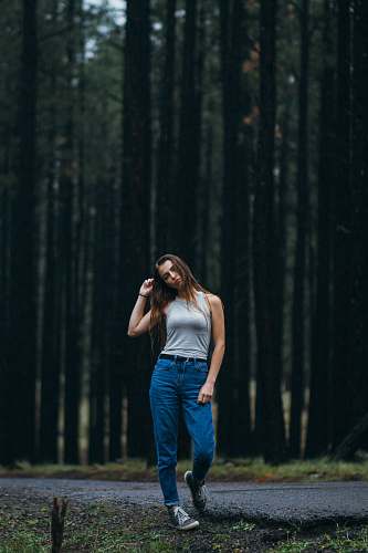 human woman standing on walkway in front of forest trees people