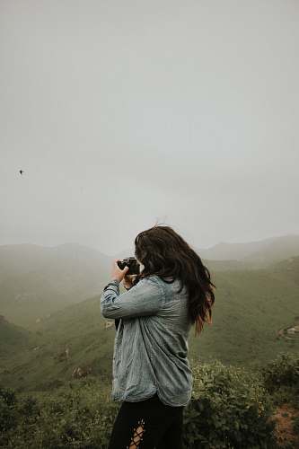 human woman taking photo of mountain during daytime people