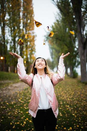 human woman throwing leaves during daytime people