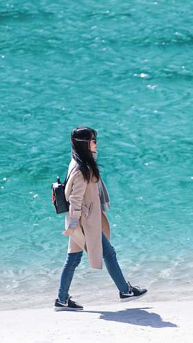 people woman walking on seashore wearing coat human