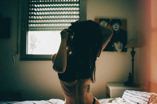 people woman wearing bra and panty sitting on bed comforter in bedroom human