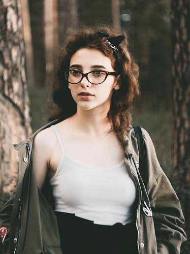 human woman wearing white camisole and gray jacket standing near tree selective focus photography people