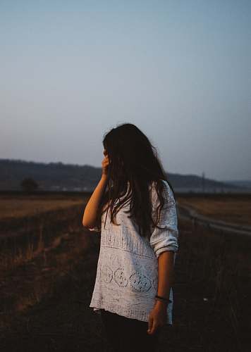 people woman wearing white lace long-sleeved shirt covering her eyes beside road human