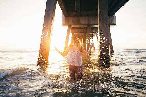girl woman stading in water under a dock during golden time blonde