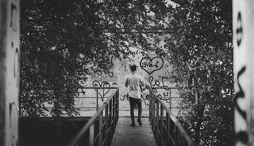 clothing grayscale photography of man standing on bridge black-and-white