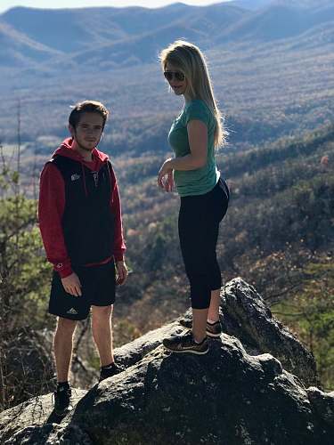 human man and woman standing on rock outdoor during daytime person