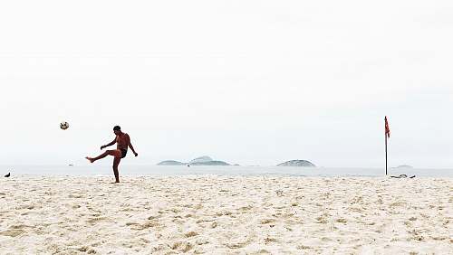 clothing man playing soccer on beach shorts