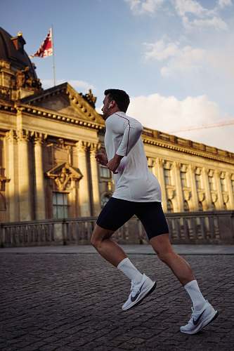footwear man running near concrete building during daytime shoe