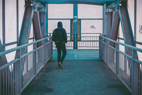 handrail person wearing black jacket with backpack walking on pathway railing