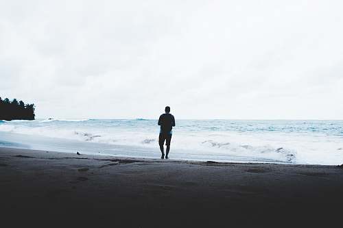 ocean man standing beside seashore sea