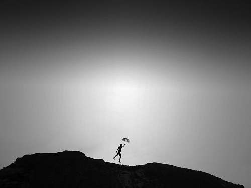 grey silhouette of man standing on cliff flare